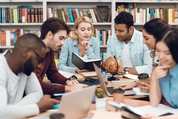 Gruppo di studenti multiculturali etnici in biblioteca.