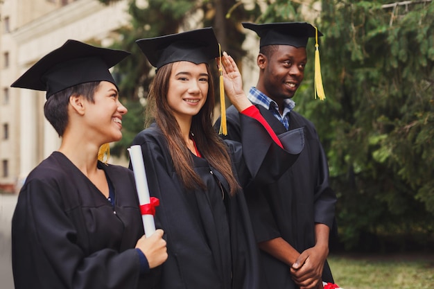 Gruppo di studenti multietnici che tengono i loro diplomi il giorno della laurea, persone felici che celebrano il grado di istruzione, spazio di copia