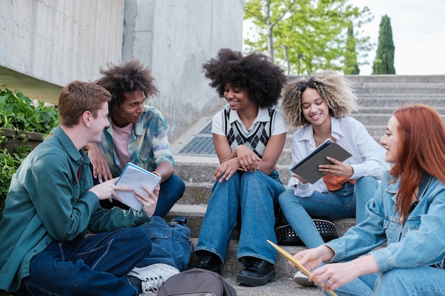 Gruppo di studenti seduti all'aperto nel campus universitario Il concetto studia gli amici dell'educazione