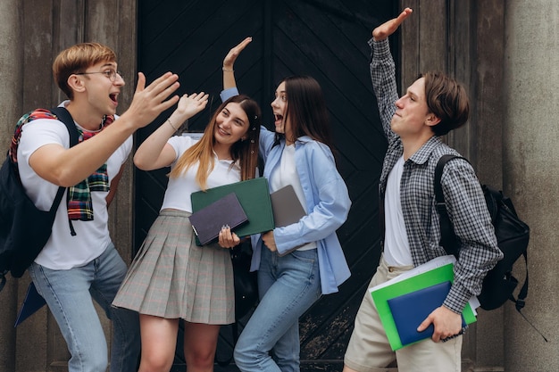 Gruppo di studenti sorridenti con le mani alzate Amici felici