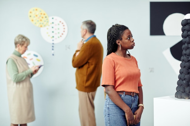 Gruppo di tre persone in visita alla mostra nel museo di arti moderne guardando installazioni di arte contemporanea