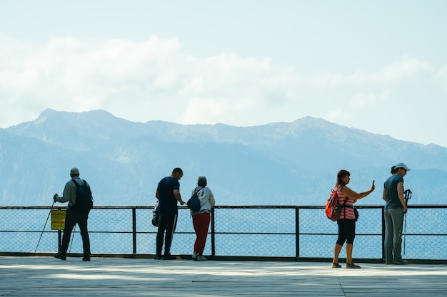 gruppo di turisti in piedi sul ponte di osservazione in montagna torna alla telecamera