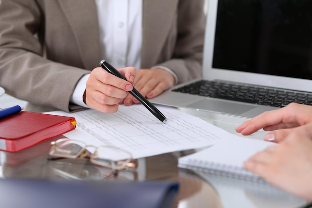 Gruppo di uomini d'affari alla riunione per discutere dei risultati finanziari. Donne che puntano al monitor del computer portatile