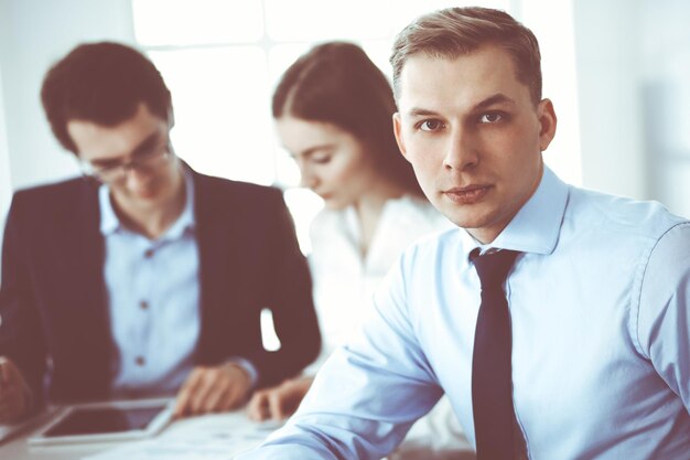 Gruppo di uomini d'affari che discutono di domande durante la riunione in un ufficio moderno. Colpo in testa dell'uomo d'affari alla trattativa. Concetto di lavoro di squadra, partnership e business.