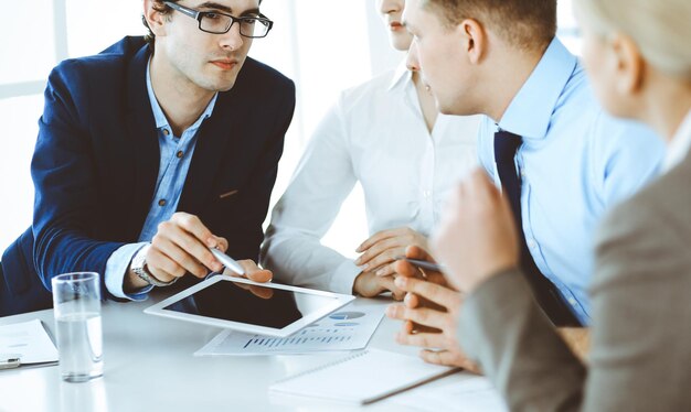 Gruppo di uomini d'affari che discutono di domande durante la riunione in un ufficio moderno. Manager in trattativa o brainstorming. Concetto di lavoro di squadra, partnership e business