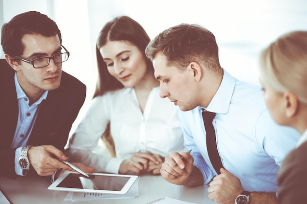 Gruppo di uomini d'affari che discutono di domande durante la riunione in un ufficio moderno. Manager in trattativa o brainstorming. Concetto di lavoro di squadra, partnership e business