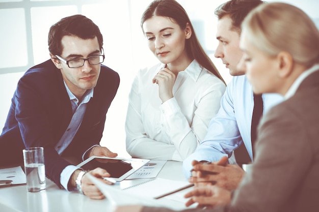 Gruppo di uomini d'affari che discutono di domande durante la riunione in un ufficio moderno. Manager in trattativa o brainstorming. Concetto di lavoro di squadra, partnership e business