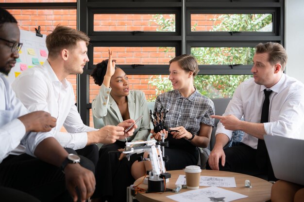 Gruppo di uomini d'affari diversi che lavorano insieme in ufficio Brainstorming sul modello di robot manuale da utilizzare per il lavoro di produzione