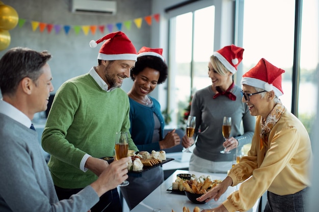 Gruppo di uomini d'affari felici che si preparano per la festa di Natale in ufficio