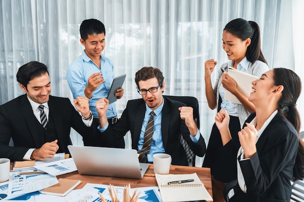 Gruppo di uomini d'affari felici in un gesto celebrativo e un lavoro di squadra efficiente di successo Impiegato di razza diversificata festeggia dopo aver fatto progressi nella pianificazione del marketing nell'ufficio aziendale Meticoloso