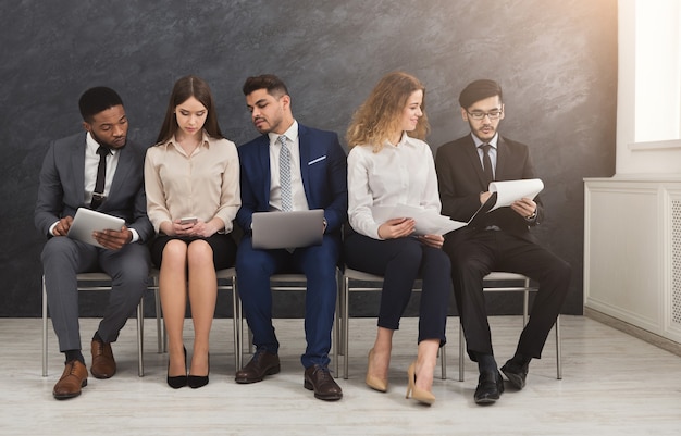 Gruppo di uomini d'affari seduti su sedie in fila e al lavoro. Team di successo che utilizza gadget, comunicazione e concetto di tecnologie moderne