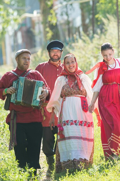 Gruppo di uomini e donne in costumi popolari russi nella celebrazione sorridente della natura