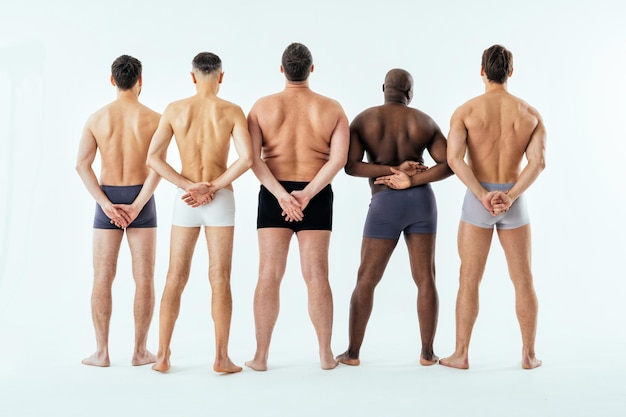 Gruppo di uomini multietnici che posano per un set di bellezza positivo per il corpo in edizione maschile. Ragazzi a torso nudo con età diverse e un corpo che indossa biancheria intima da boxer