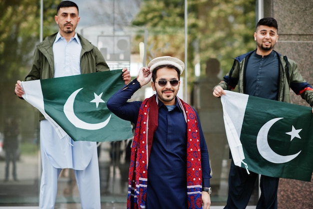 Gruppo di uomini pakistani che indossano abiti tradizionali salwar kameez o kurta con bandiere pakistane.