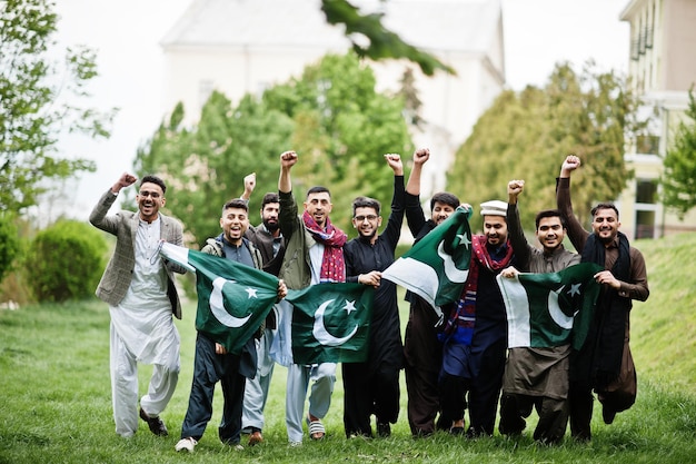 Gruppo di uomini pakistani che indossano abiti tradizionali salwar kameez o kurta con bandiere pakistane.