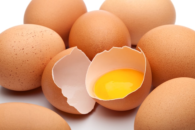 Gruppo di uova marroni fresche con un uovo aperto
