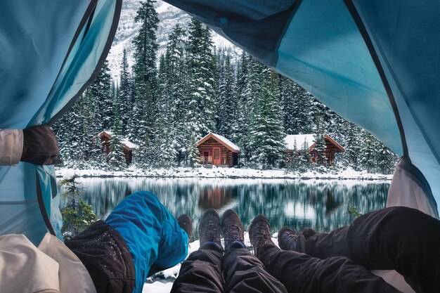 Gruppo di viaggiatori che aprono la tenda con lodge in legno nella foresta di neve sul lago O'hara al parco nazionale di Yoho, Canada