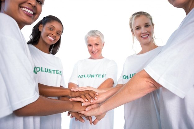 Gruppo di volontari femminili con le mani che sorridono insieme alla macchina fotografica