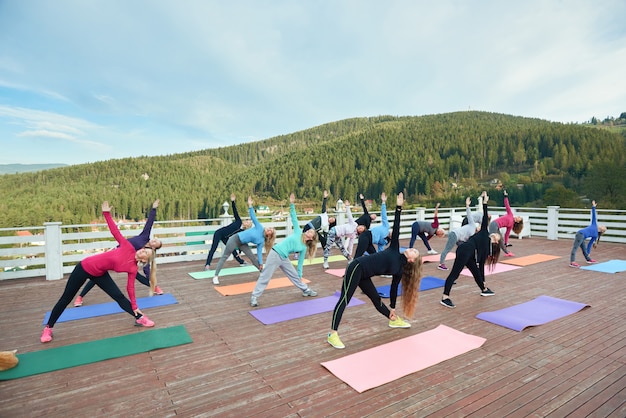 Gruppo di yoga che pratica triangolo rotante.