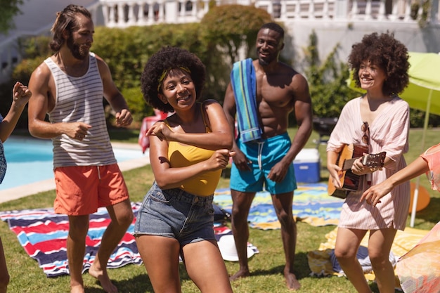 Gruppo eterogeneo di amici che si divertono e ballano a una festa in piscina. Uscire e rilassarsi all'aperto in estate.