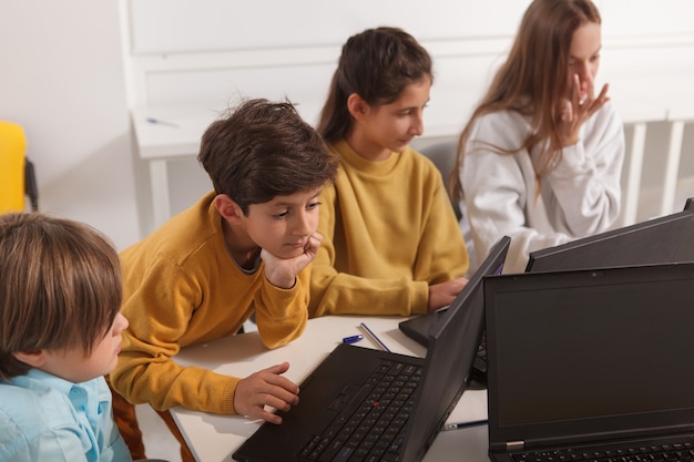 Gruppo eterogeneo di bambini che lavorano su laptop sulla lezione di scuola di computer