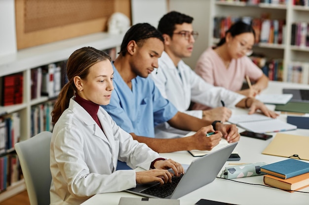 Gruppo eterogeneo di giovani studenti di medicina seduti in fila durante la lezione o il seminario