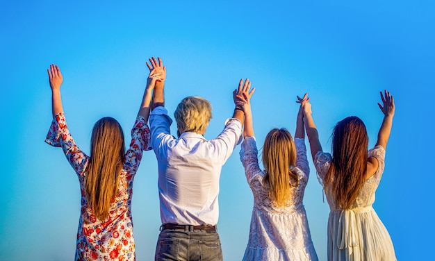 Gruppo mani in alto indietro Gruppo di donne uomo che si diverte e insieme salutano Giovani attività per il tempo libero tutte le mani in alto Gruppo ragazze maschi in piedi insieme tenendosi per mano alzare le mani