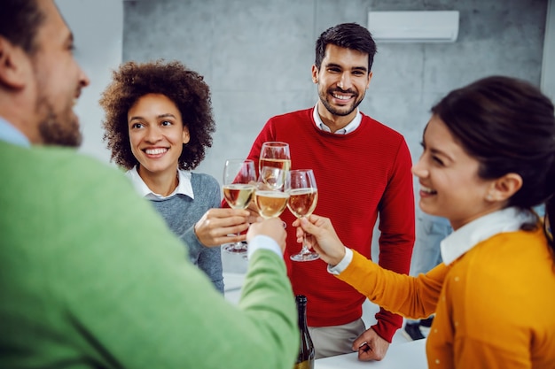 Gruppo multiculturale di colleghi che celebrano il successo in sala riunioni. Colleghi che tostano con champagne.