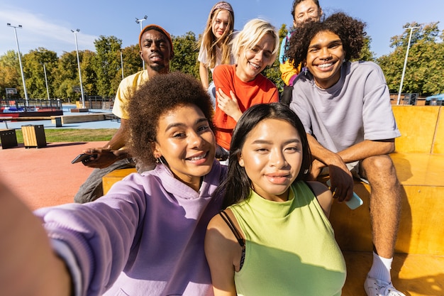 Gruppo multiculturale di giovani amici che si uniscono all'aperto e si divertono - Ragazzi alla moda e alla moda che si riuniscono allo skate park urbano