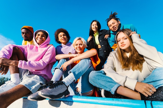 Gruppo multiculturale di giovani amici che si uniscono all'aperto e si divertono - Ragazzi alla moda e alla moda che si riuniscono allo skate park urbano