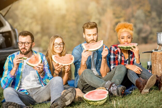 Gruppo multietnico di amici che fanno un picnic, mangiano anguria durante la ricreazione all'aperto