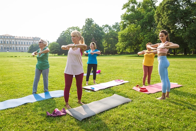 Gruppo multietnico di donne anziane che si allenano al parco con istruttore di fitness - Anziani attivi che fanno sport nella natura