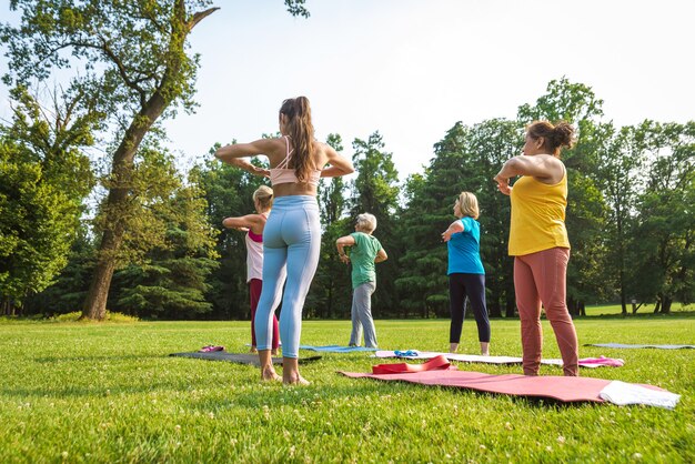 Gruppo multietnico di donne anziane che si allenano al parco con istruttore di fitness - Anziani attivi che fanno sport nella natura