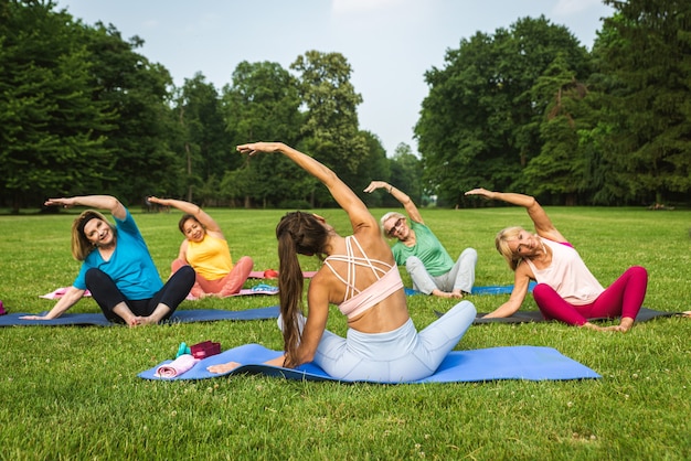 Gruppo multietnico di donne anziane che si allenano al parco con istruttore di fitness - Anziani attivi che fanno sport nella natura