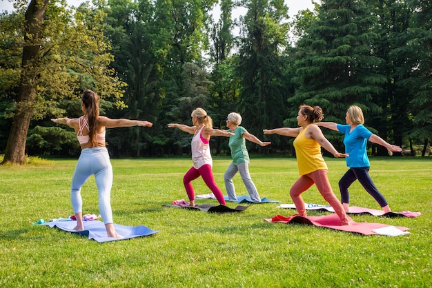 Gruppo multietnico di donne anziane che si allenano al parco con istruttore di fitness - Anziani attivi che fanno sport nella natura