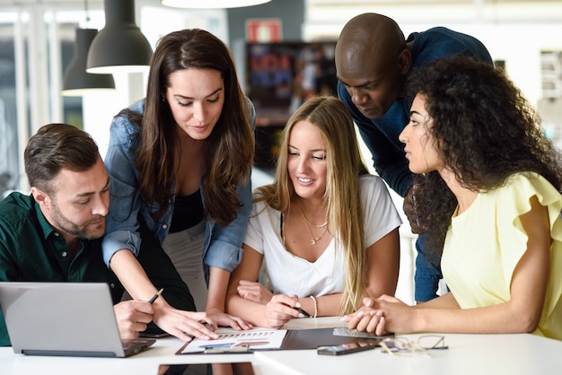 Gruppo multietnico di giovani uomini e donne che studiano al chiuso.