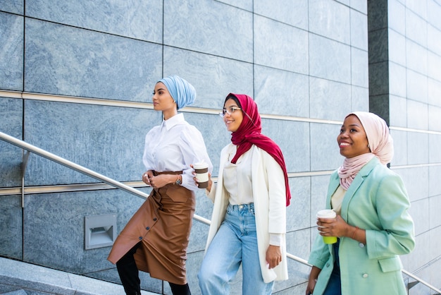 Gruppo multietnico di ragazze musulmane che indossano abiti casual e tradizionali legami hijab e si divertono all'aperto - 3 ragazze arabe