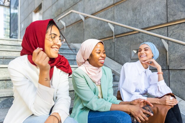 Gruppo multietnico di ragazze musulmane che indossano abiti casual e tradizionali legami hijab e si divertono all'aperto - 3 ragazze arabe