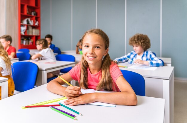 Gruppo multirazziale di bambini della scuola primaria - Scolari giocosi che si godono l'orario scolastico e le lezioni con l'insegnante e i compagni di classe