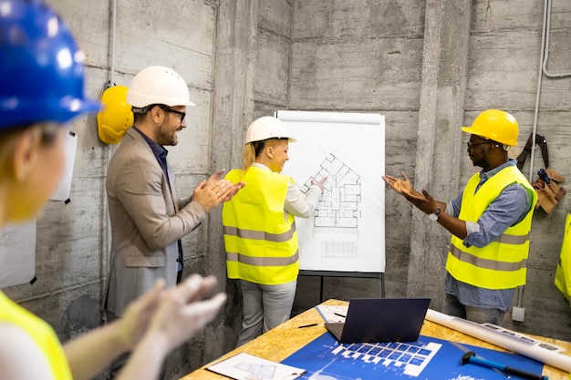 gruppo positivo di ingegneri strutturali in cantiere che si incontrano ridendo e battendo le mani