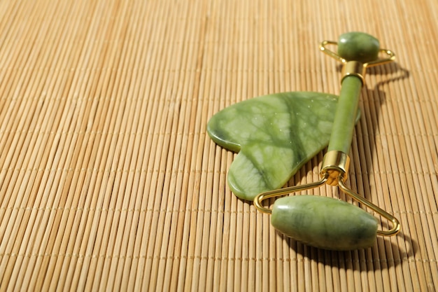 Gua sha e rullo facciale su sfondo di bambù