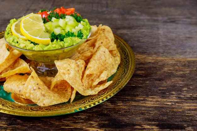 Guacamole con tortilla chips in una ciotola su uno sfondo di legno scuro. Vista dall&#39;alto con lo spazio della copia.