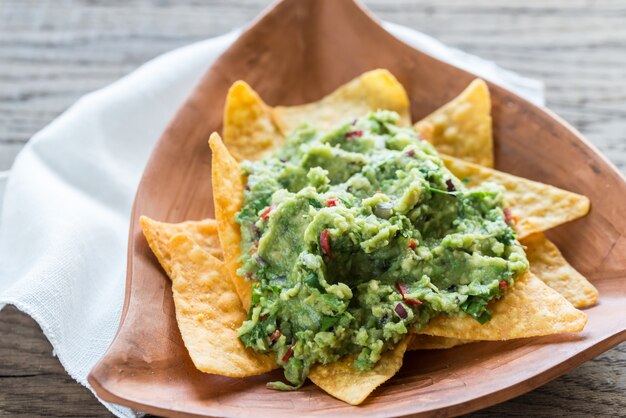 Guacamole con tortilla chips sulla superficie in legno