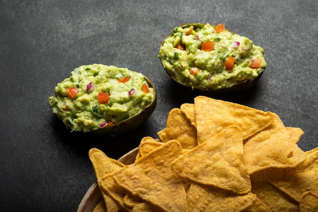 Guacamole di salsa latinoamericana tradizionale in patatine fritte di nachos messicane di avocado tagliato a metà