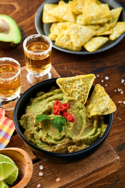 Guacamole. Salsa messicana tradizionale latinoamericana in una ciotola nera con avocado e ingredienti