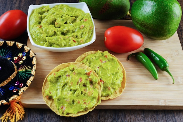 Guacamole servito su un piatto bianco su un tavolo di legno. Ingredienti del guacamole.