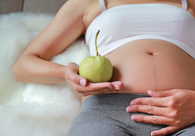 Guaiava della tenuta della donna incinta alla sua pancia. Concetto di dieta. Uno stile di vita sano.