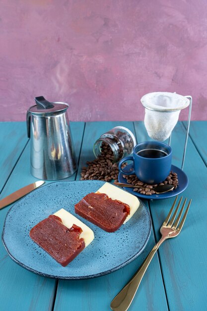 Guaiava dolce con formaggio circondato da tazza di posate e chicchi di caffè su un tablevertical blu