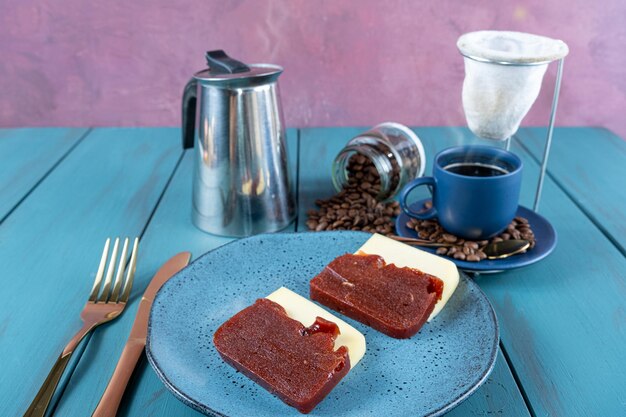 Guaiava dolce con formaggio circondato da tazza di posate e chicchi di caffè su un tavolo blu