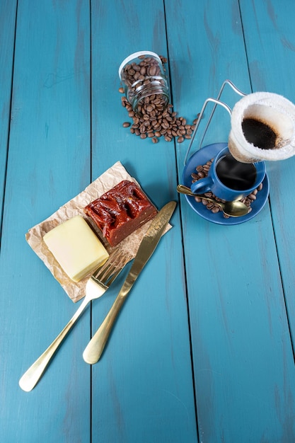 Guaiava dolce con formaggio su carta marrone circondata da posate di fagioli e una tazza di caffèverticval